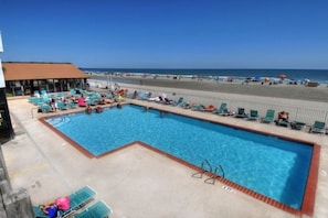 Ein Pool mit Liegestühlen und Blick auf den Strand.