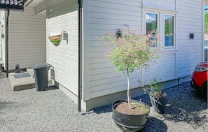 Ein Haus mit einem kleinen Baum im Blumentopf, einer Bärenstatue und einem roten Auto vor der Tür.