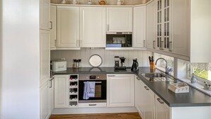 Eine Küche mit weißen Schränken, einem eingebauten Backofen, einer Kaffeemaschine und einem Spülbecken.