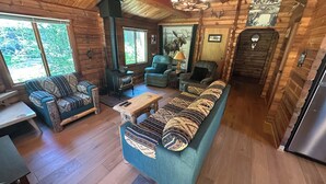 A log cabin interior with a sofa, chairs, a table, a fireplace, and a refrigerator. - Cozy Donner Lake Cabin, Mountain Setting & Beach Access (Truckee)