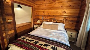 A wooden cabin-style room with a bed, nightstands, a lamp, and a wall-mounted light fixture. - Cozy Donner Lake Cabin, Mountain Setting & Beach Access (Truckee)
