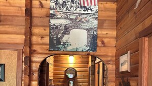 A wooden log cabin interior with a hallway leading to a door, a mounted American flag, and a rustic wall decor. - Cozy Donner Lake Cabin, Mountain Setting & Beach Access (Truckee)