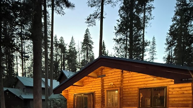 A wooden cabin with a deck, red and white chairs, and a table. - Cozy Donner Lake Cabin, Mountain Setting & Beach Access (Truckee)