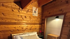 A wooden cabin-style bedroom with a bed, a nightstand, a dresser, and a mirror. - Cozy Donner Lake Cabin, Mountain Setting & Beach Access (Truckee)