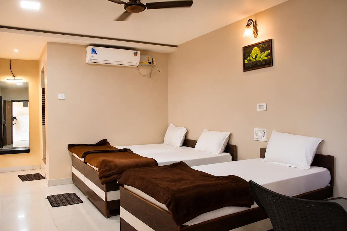 Hotelkamer met twee bedden, een plafondventilator, een airconditioningapparaat, een wandlamp en een ingelijste foto.