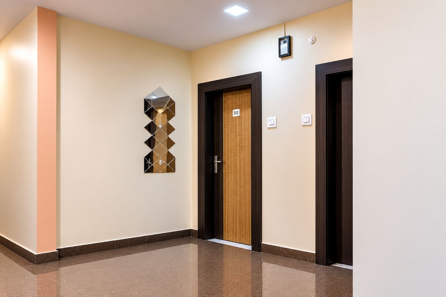 A hallway with a polished floor, a decorative wall piece, and two doors with a number sign.