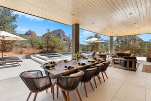 An outdoor dining area with a pool, chairs, and a view of the mountains. - Luma Ridge - `26 Luxury Build, Pool & Spa, Views (Sedona)