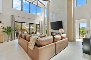 A spacious living room with a large leather sofa, a flat-screen TV, and a fireplace. - Luma Ridge - `26 Luxury Build, Pool & Spa, Views (Sedona)