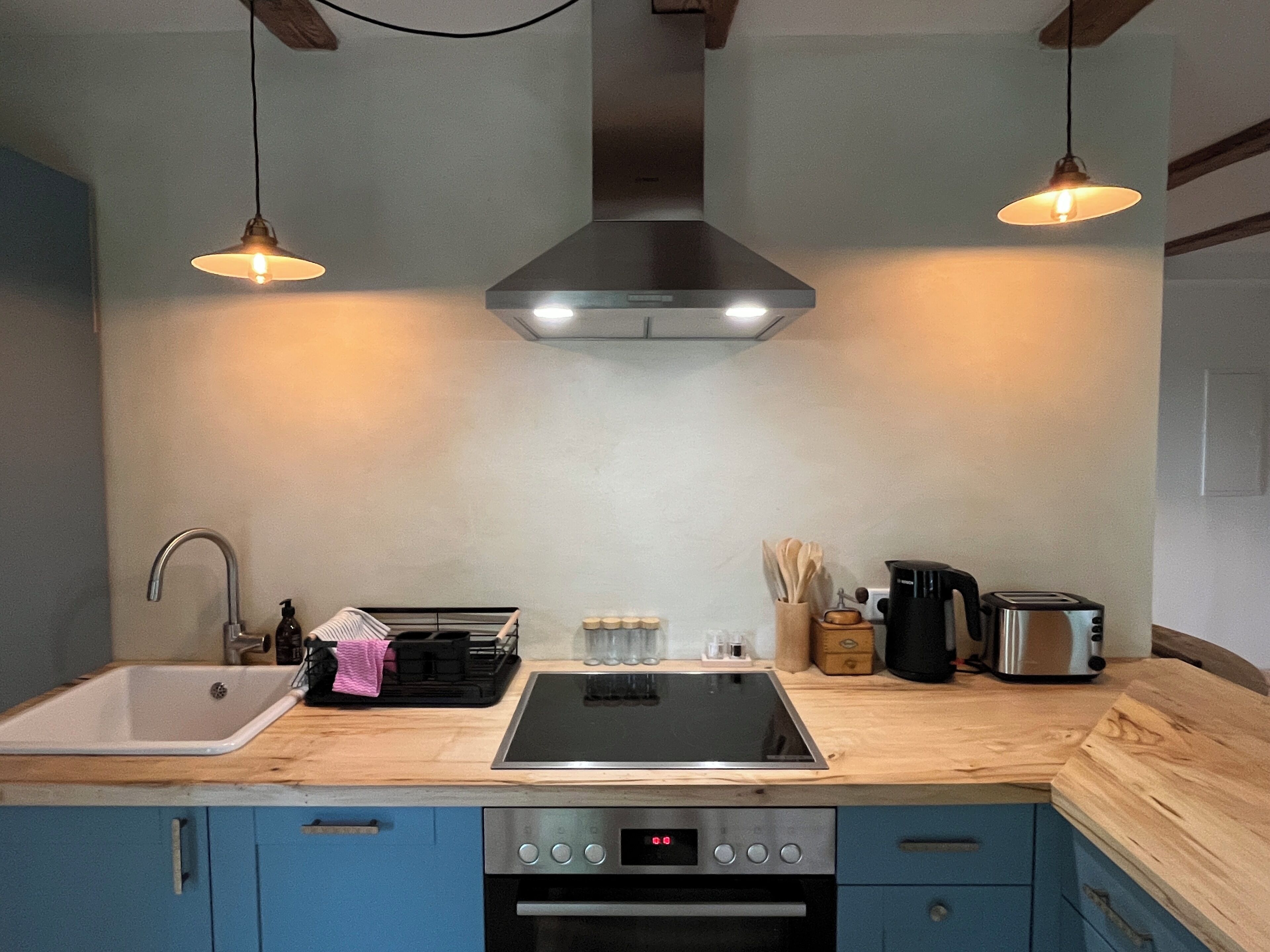 Uma cozinha com forno embutido, pia, fogão e duas luminárias pendentes.