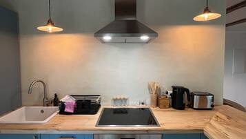 Uma cozinha com forno embutido, pia, fogão e duas luminárias pendentes.
