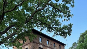 A multi-story brick building with large windows and a stone wall foundation.