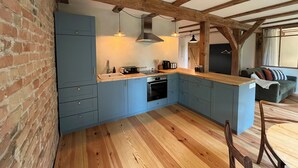 A kitchen with blue cabinets, wooden beams, a wooden countertop, and a dining area with a table and chairs.