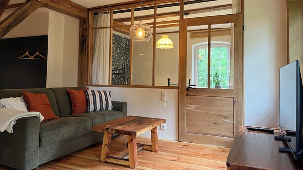 A cozy living room with a wooden ceiling, a sofa, a coffee table, and a TV stand.