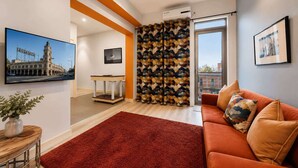 A modern living room with a red carpet, orange sofa, and a city view. - Serenity Cloud Apartment in Vibrant Footscray (Footscray)