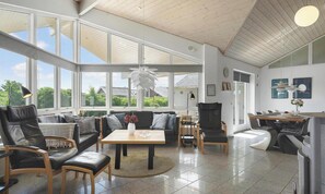 A spacious living area with a large window, a dining table, and a kitchen area. - Amazing home in Hvide Sande with sauna (Hvide Sande)