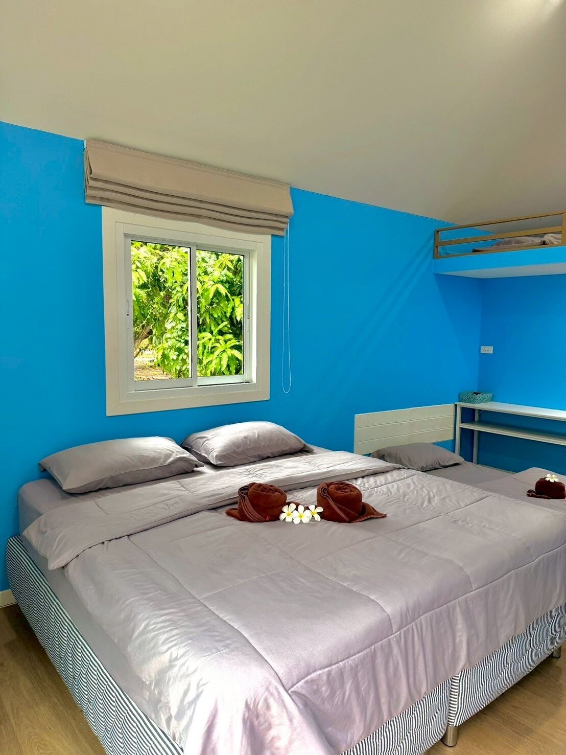 A bedroom with a bed, pillows, a window, a bunk bed, and a bedside table.