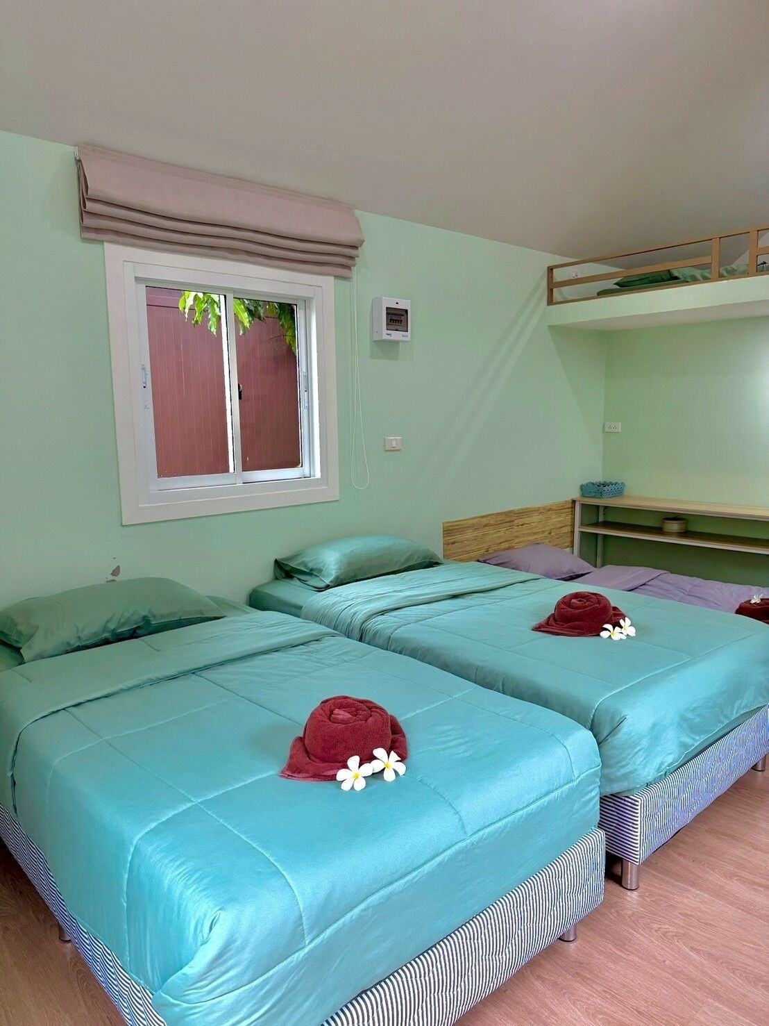 A room with two beds, a window with a view, a bunk bed, and a small table.
