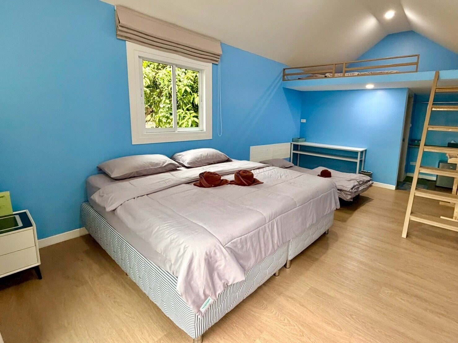 A bedroom with a bed, a window, a bunk bed, and a bedside table.