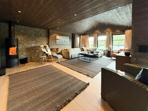 A cozy living room with a stone wall, a fireplace, a sofa, and a large rug. - New cabin with activities and fire pit near Voss (Voss)