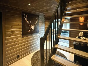 Ein Holzinnenraum mit einer Treppe, Wanddekoration aus Hirschgeweihen und einem runden Teppich.