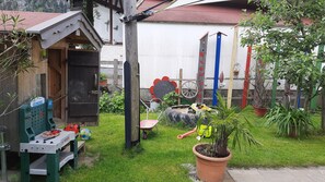 Ein Garten mit einer Werkbank, einer Schubkarre und Topfpflanzen.