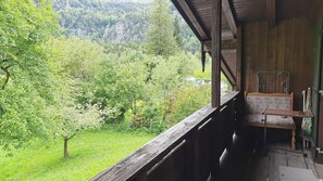 Un balcón de madera con un banco, con vistas a un paisaje verde exuberante y una montaña.