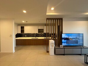 Een moderne woonkamer met een flatscreen-televisie, een waterdispenser en een keuken in de achtergrond.