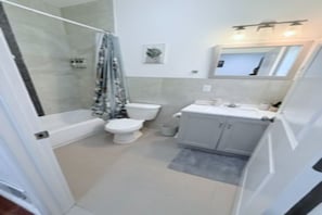A bathroom with a shower, toilet, sink, and mirror. - Bright 4-bedroom/2 bath in Jersey City/Near NYC /MetLife stadium /FIFA World Cup (Jersey City)