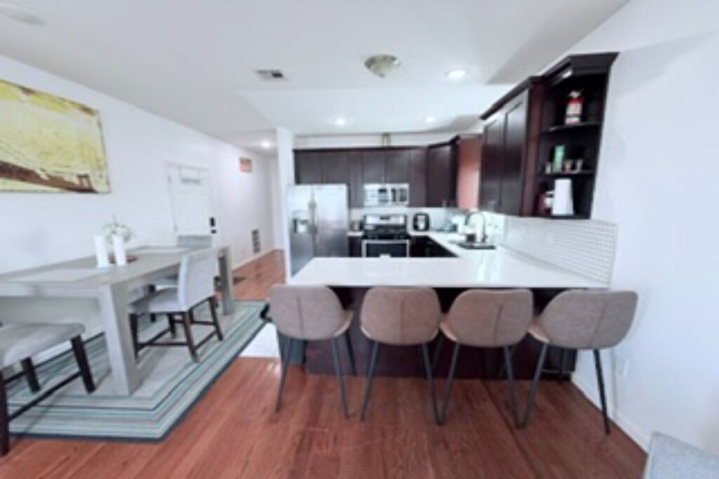 A modern kitchen with a central island, bar stools, and dark cabinetry.