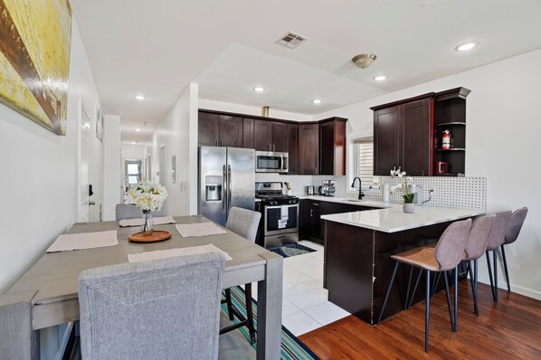 A modern kitchen with dark wood cabinets, stainless steel appliances, and a central island with bar stools.