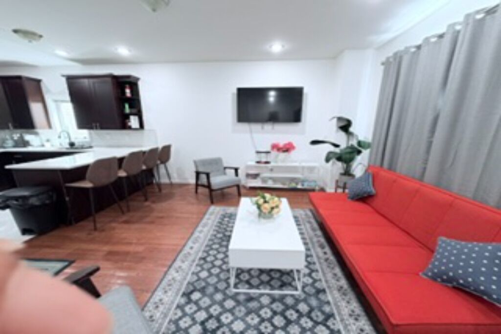 Un salon moderne avec un canapé rouge, une table basse blanche et un téléviseur fixé au mur.