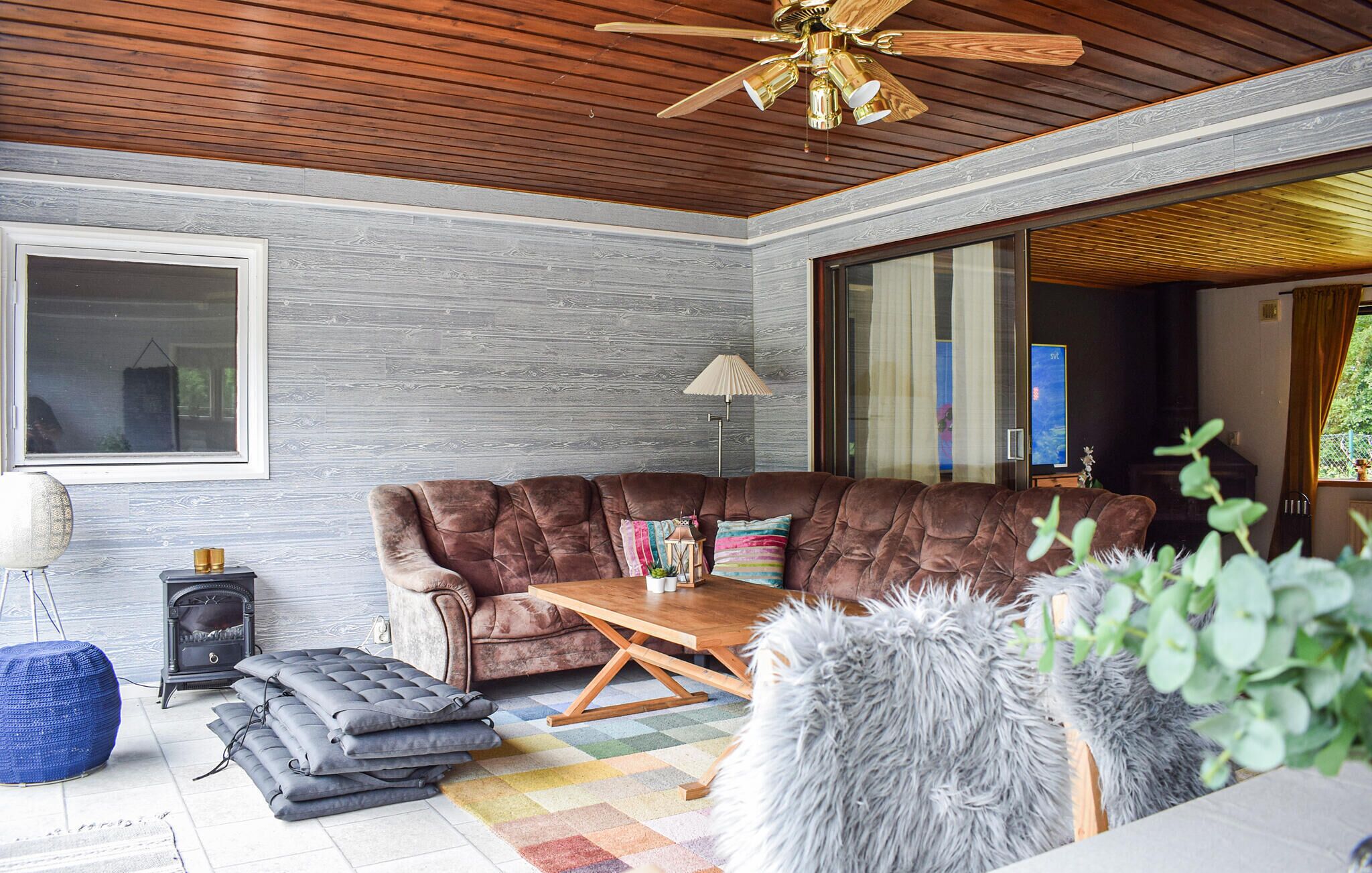 Een moderne woonkamer met een bruine modulaire bank, een houten salontafel, een open haard en een plafondventilator.