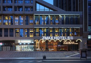 A hotel with a modern facade, multiple floors, and a prominent entrance with illuminated signage. - Zmax Manxi Hotel (CHENGDU)