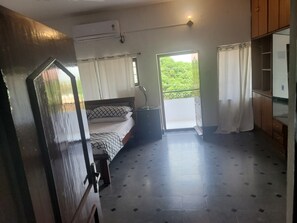 A room with a bed, an air conditioning unit, a door, a window, and a balcony.