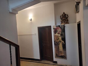 Un pasillo con una puerta, una lámpara de pared y un cuadro enmarcado.