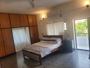 A bedroom with a bed, wardrobe, air conditioning unit, and a view of greenery outside. - MAJESTIC MAHINDRA HILLS HEIGHTS: BR1 (Hyderabad)