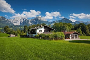 Ein Haus mit großem Rasen, einer Garage und Bergen im Hintergrund.