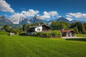 A house with a large lawn, a garage, and mountains in the background. - Vacation Rental No. 1, 1 to 2 people, 55 square meters, non-smoking, 1 bedroom, terrace (Schönau am Königssee)
