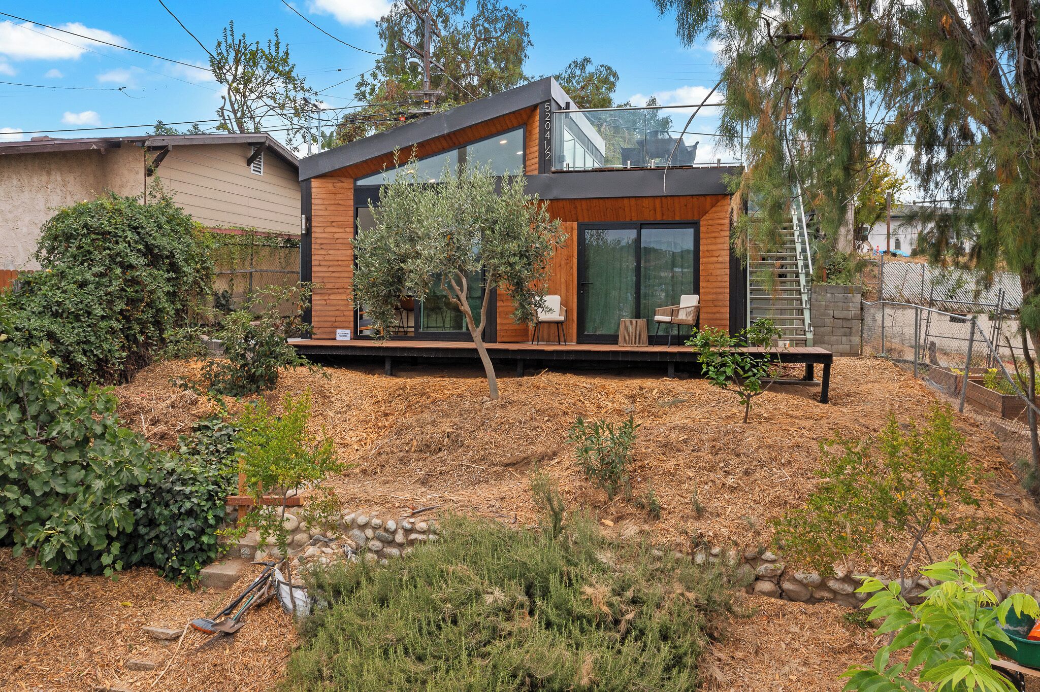 A modern house with a large glass window, a wooden deck, and a stone wall.