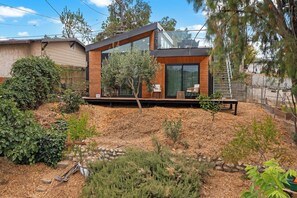 Een modern huis met een groot glazen raam, een houten terras en een stenen muur.