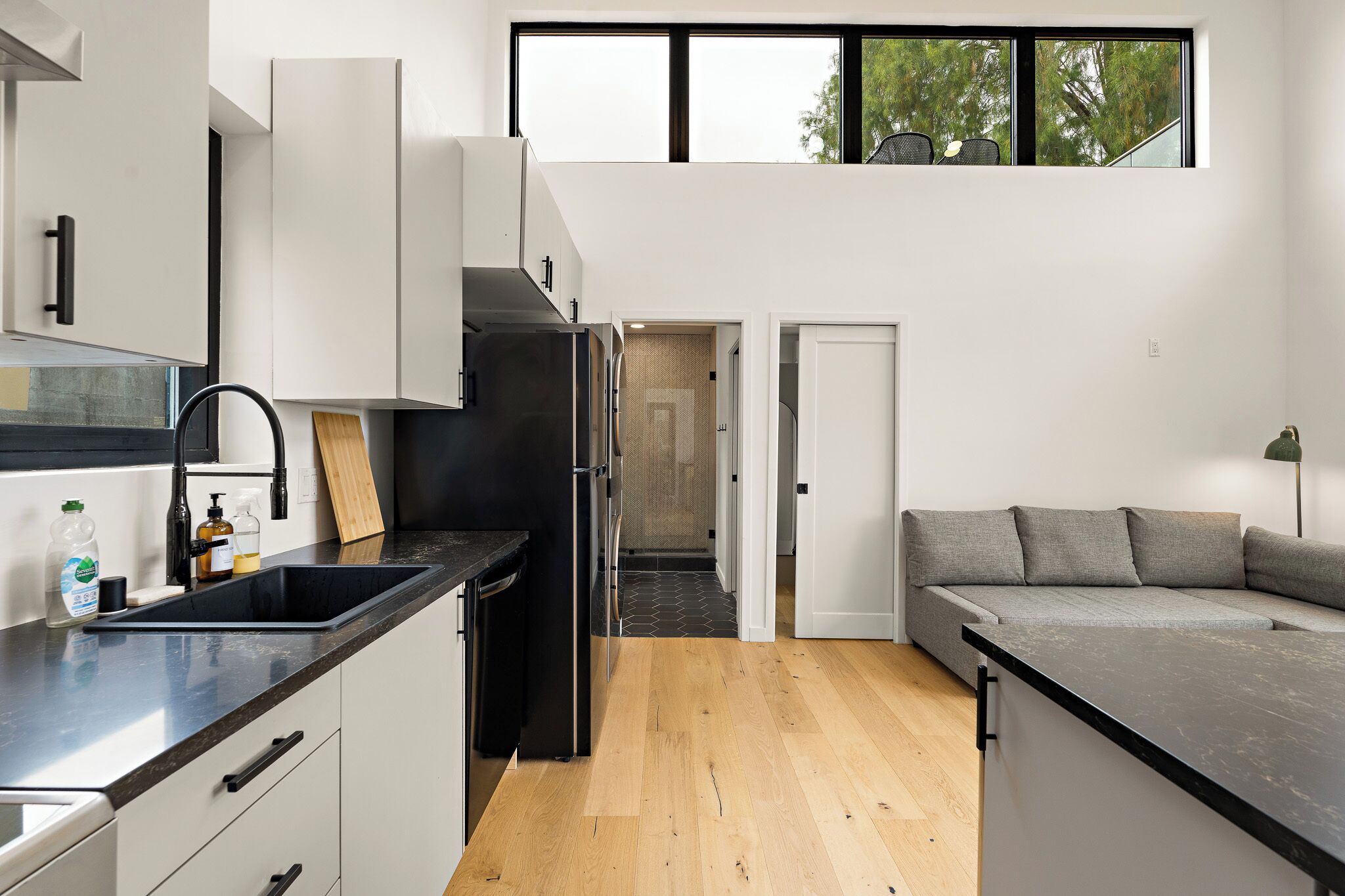 A modern kitchen with a black refrigerator, white cabinets, and a wooden countertop.