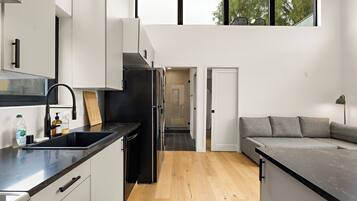 A modern kitchen with a black refrigerator, white cabinets, and a wooden countertop.