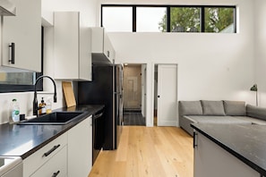 Een moderne keuken met een zwarte koelkast, witte kasten en een houten aanrecht.