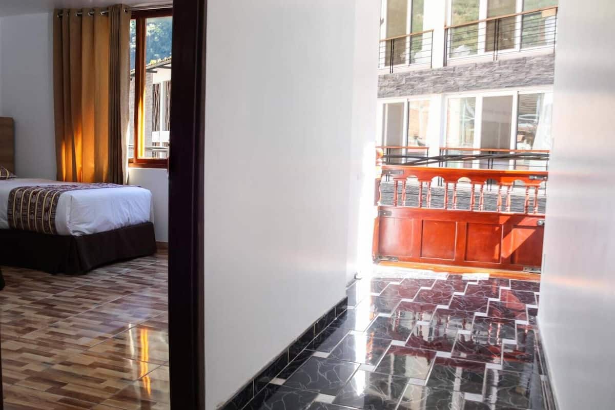 Une chambre d’hôtel avec un lit, une vue sur le balcon extérieur et un sol carrelé.