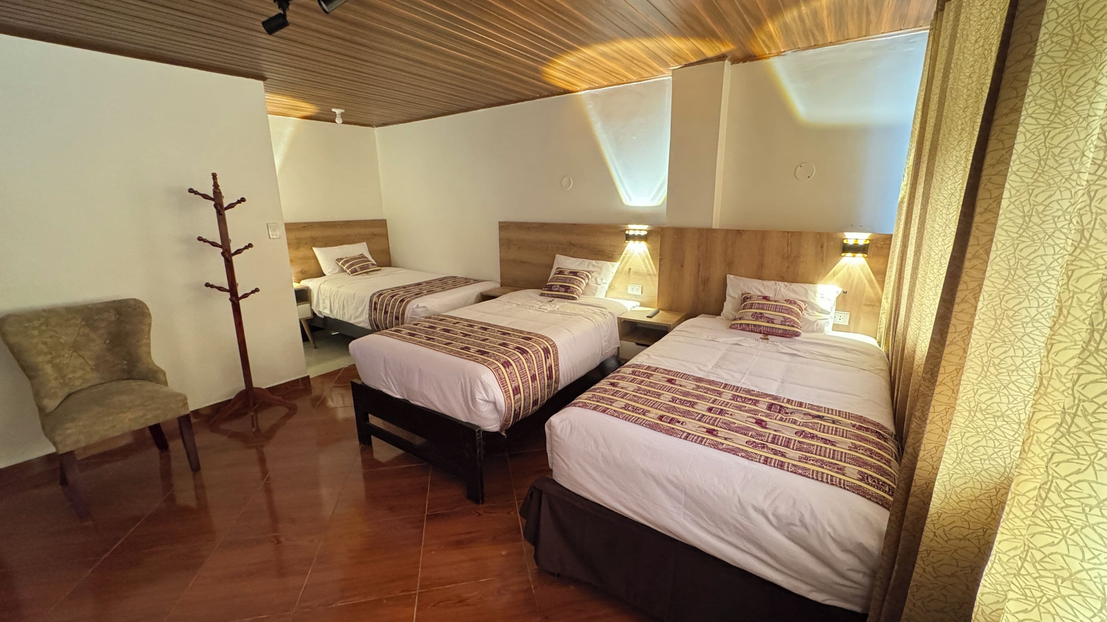 Ein Zimmer mit zwei Betten, einem Sessel und einem Kleiderständer.