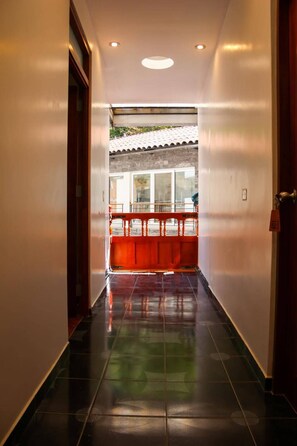 A hallway with a tiled floor leading to a balcony with a railing. - Apachetas Hotel  (Aguas Calientes)