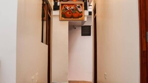 A hallway with a tiled floor, recessed ceiling lights, and a framed artwork hanging on the wall.