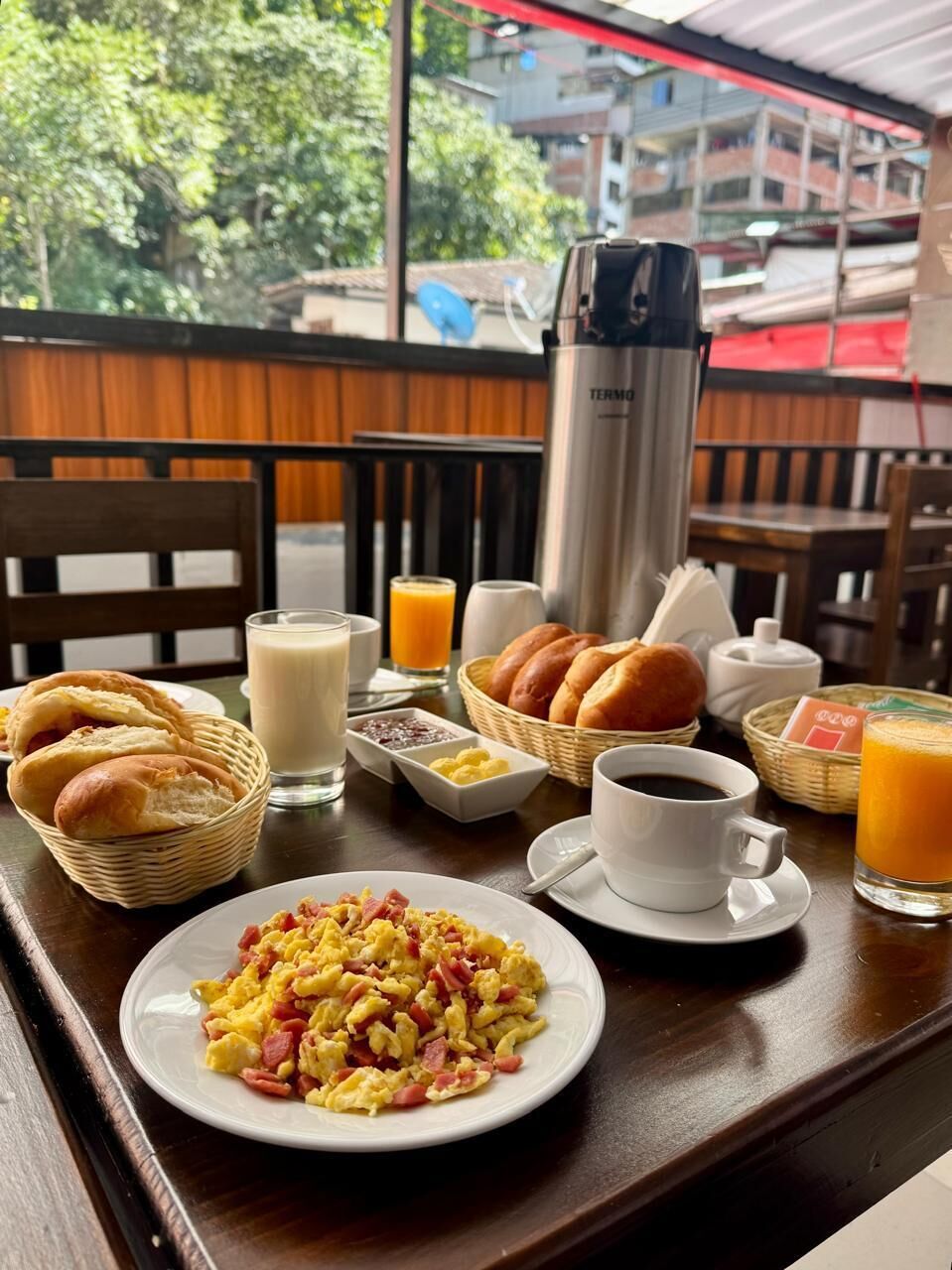Ett frukostbord med äggröra, rostat bröd, juice och en kaffekanna.