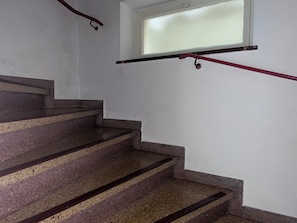 Portaat, joiden askelmat ovat graniittia ja joissa on kaide, johtavat huoneeseen, jossa on ikkuna.