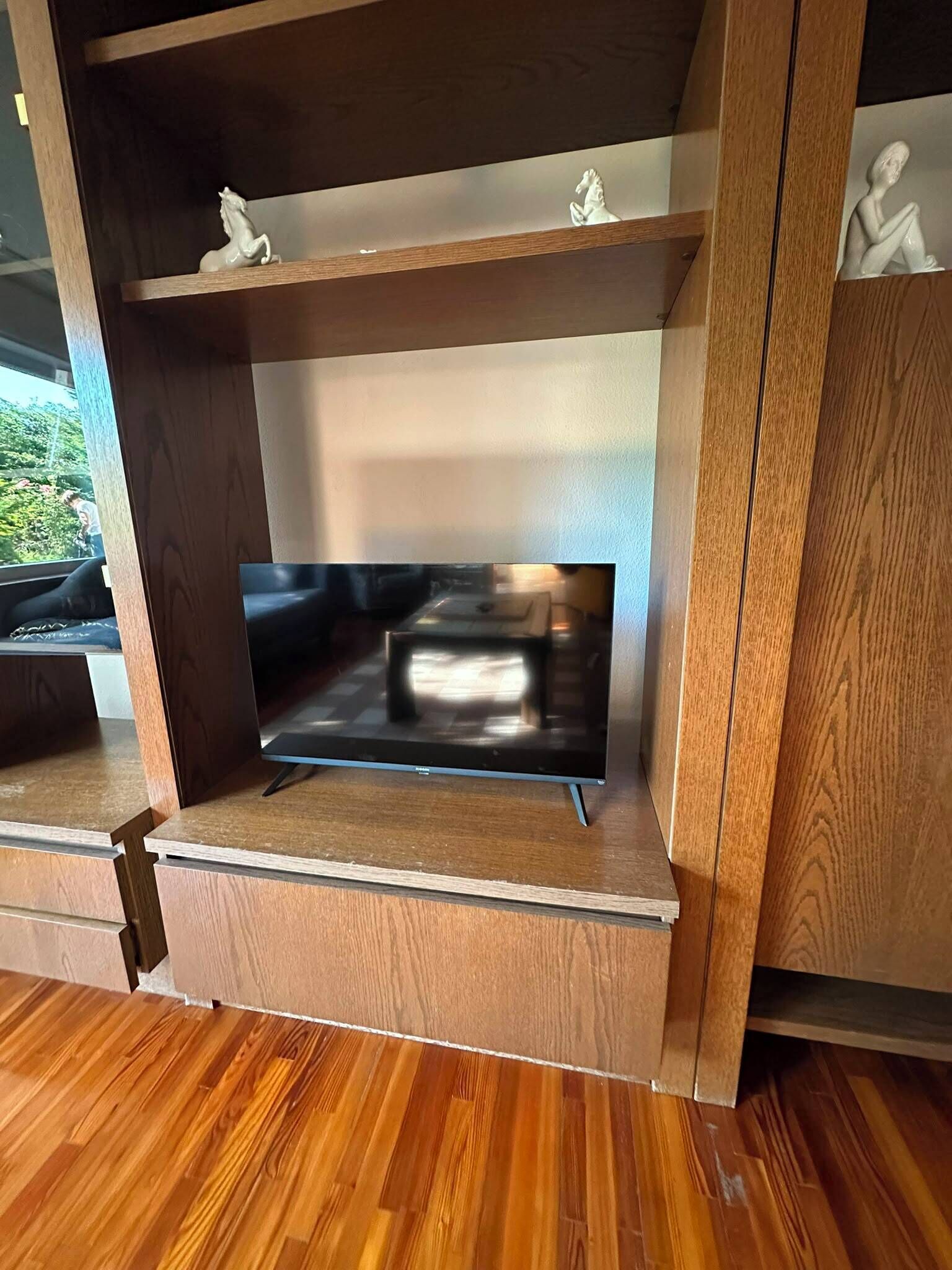 Ein Holz-Multifunktionsmöbel mit einem Flachbildfernseher, Regalen und Dekoration.